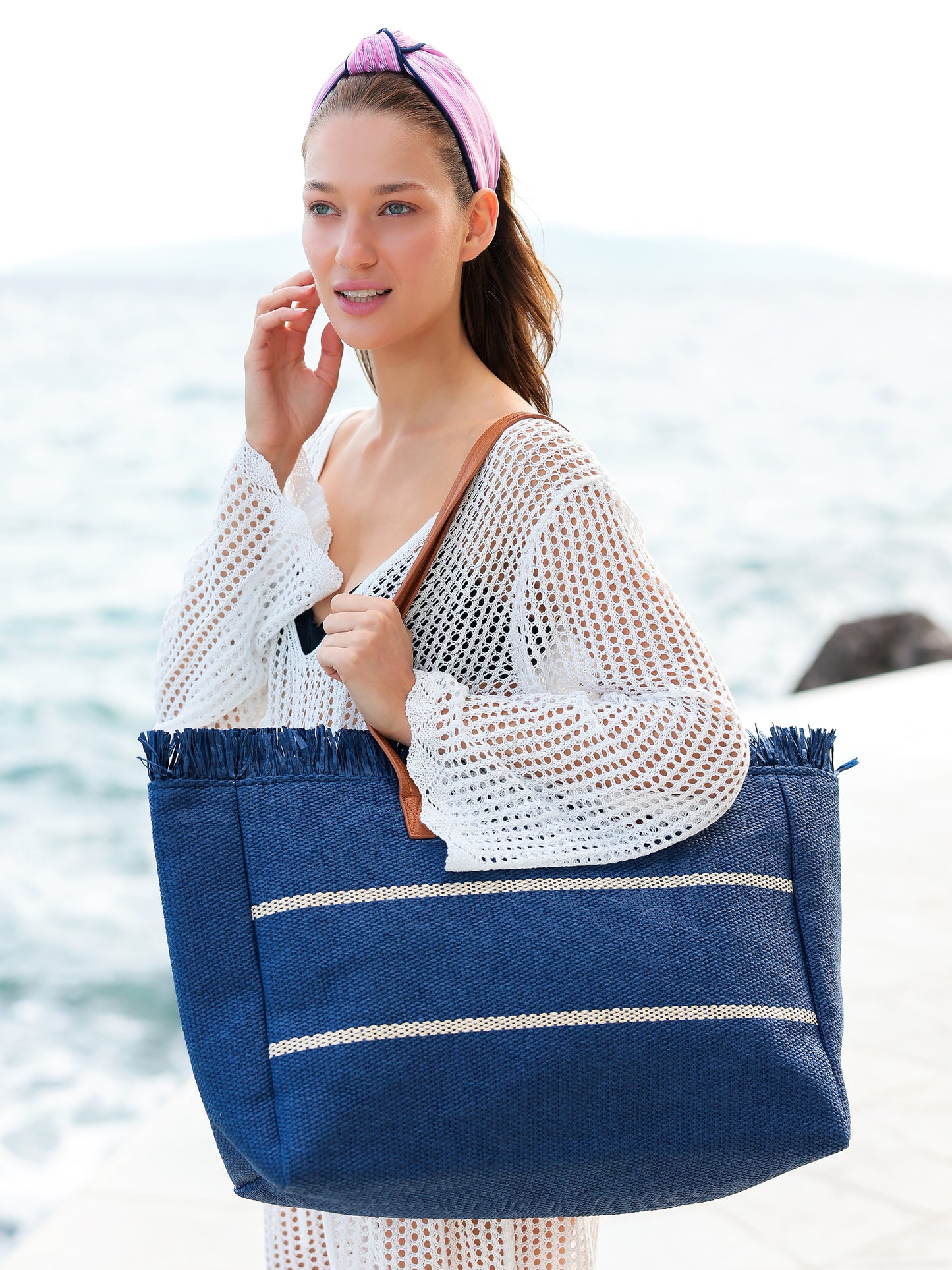 Navy tote bag with cream horizontal stripes, long tan handles, fringed sides