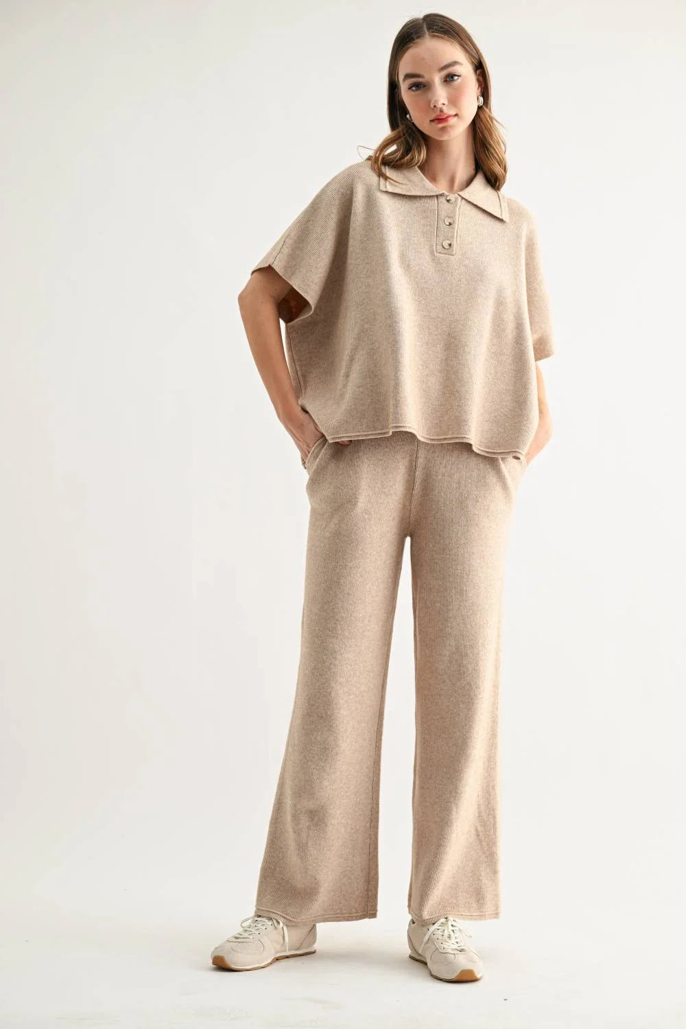 Woman wearing a beige collared knit top and wide-leg pants with sneakers