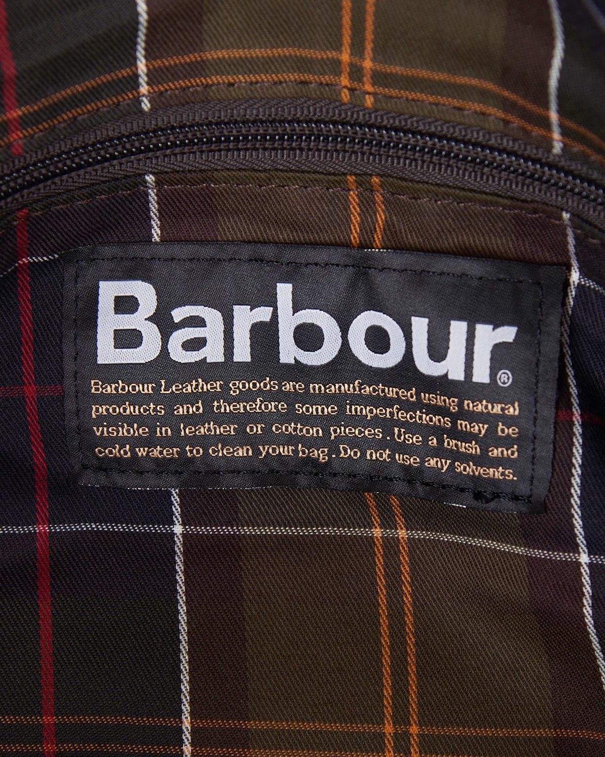 Close-up of Barbour label sewn inside Wax Holdall with plaid fabric lining detail