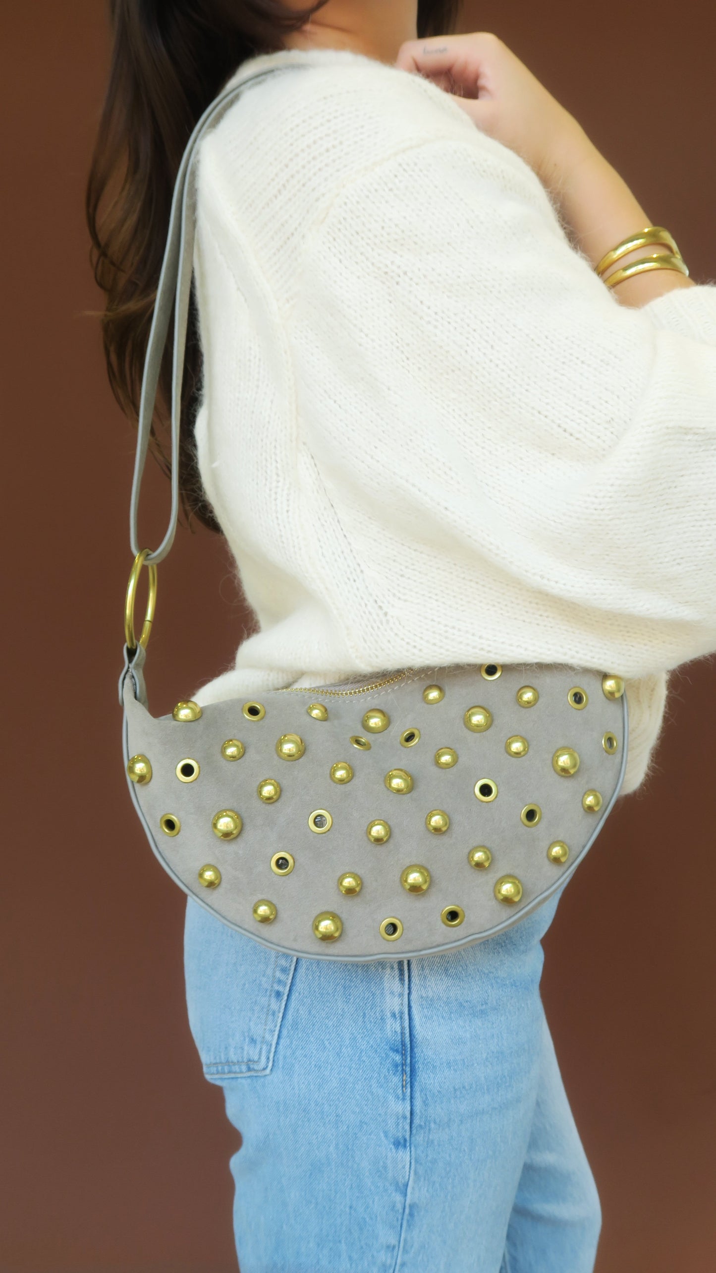 Maeve Studded Bag worn crossbody in gray leather with gold-tone stud pattern