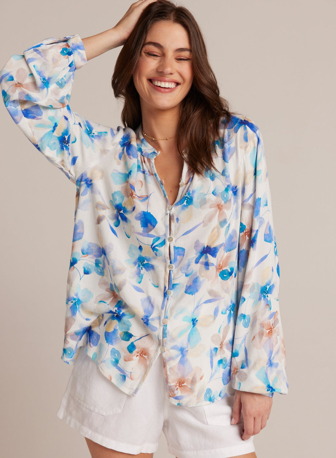 Smiling woman wearing a flowy, floral print Button Loop Front Shirt in shades of blue and tan paired with white shorts, showcasing effortless Hill Country style.