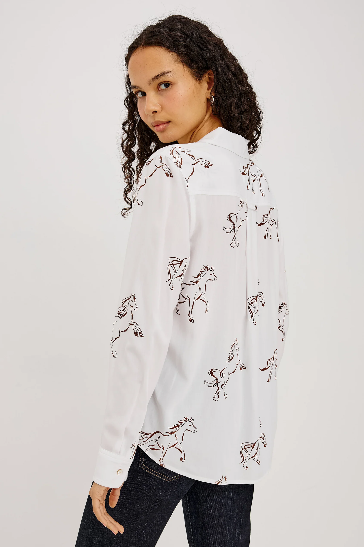 Woman wearing a white horse print shirt and dark jeans