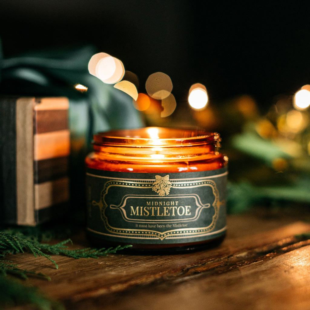 Midnight Mistletoe Candle, lit in amber glass jar with ornate label
