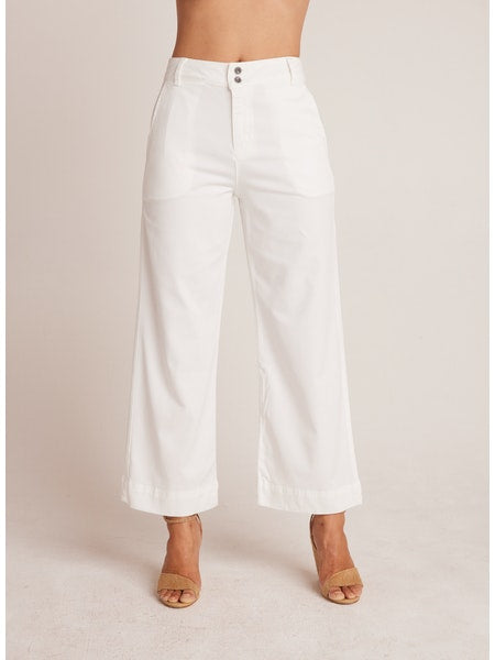 Woman wearing white Saige - Wide Leg Crop pants with a high waist and double-button closure, paired with tan open-toe heels, featuring a relaxed and breathable fit.