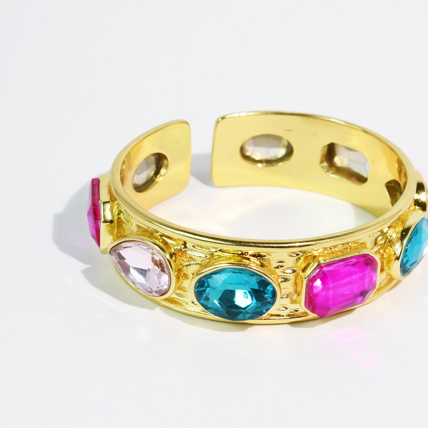 Multi Glow Bangle gold cuff with bright pink, blue, and clear gemstones from Treasure Jewels