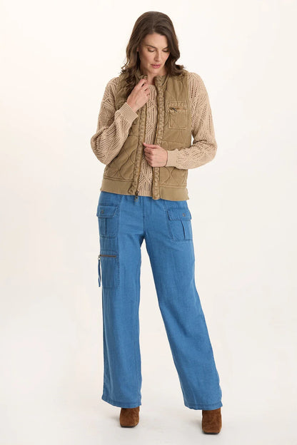 Aeric Quilted Vest in beige cotton with pockets styled over beige knit sweater and blue pants