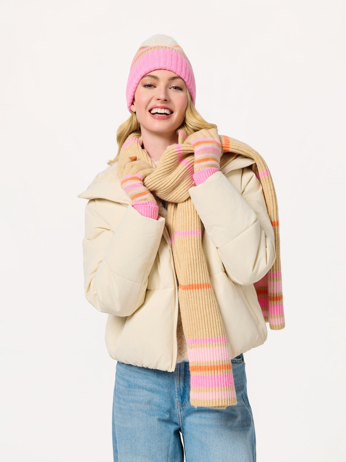 Woman wearing Elle Scarf striped in beige, pink, and orange with knit hat and gloves at HCO FBG