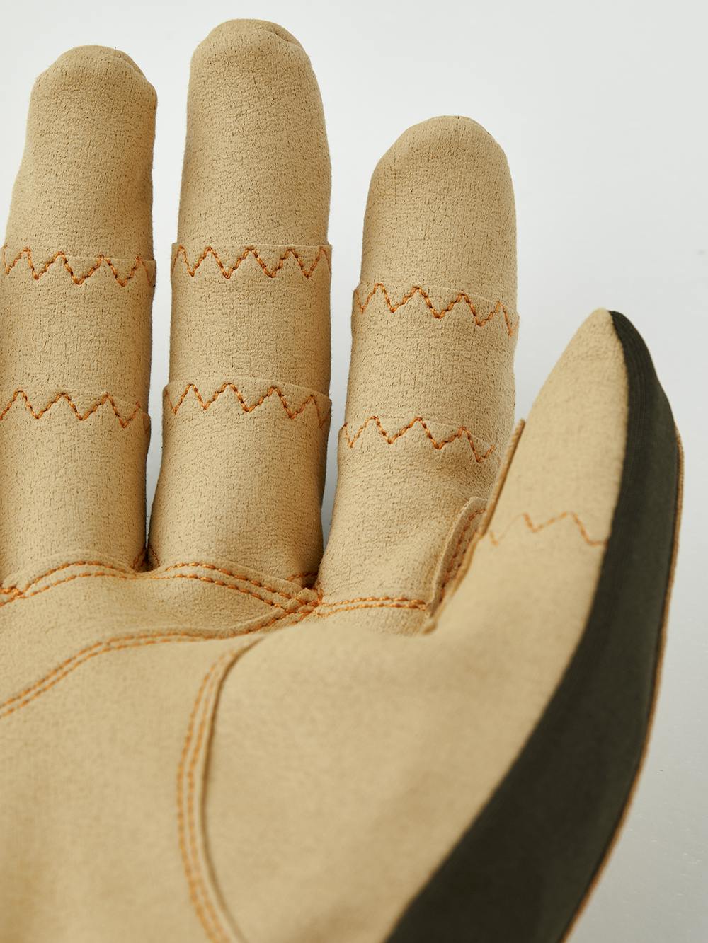 Close-up of tan and dark green fabric glove showcasing detailed zigzag stitching, designed for comfort and durability in the Ergo Grip Tactility Dk Forest.