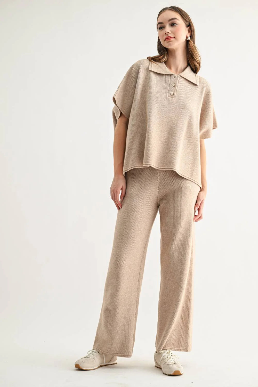 Woman wearing a beige knit polo top, wide-leg pants, and white sneakers