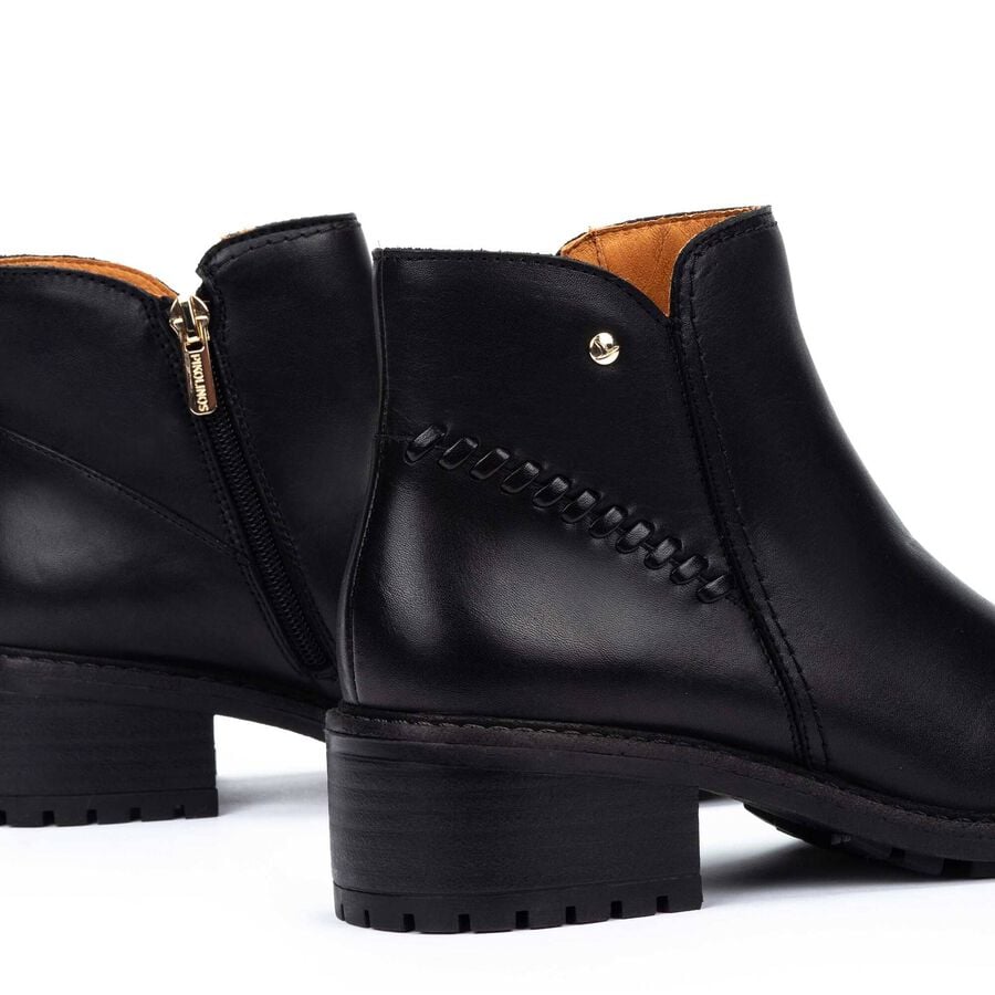 Botines negros con cremallera interior y detalle de botón metálico
