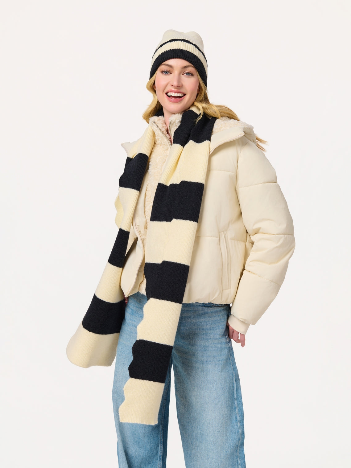 Woman wearing Scala Striped Scarf in black and cream with cream jacket and striped hat at HCO FBG