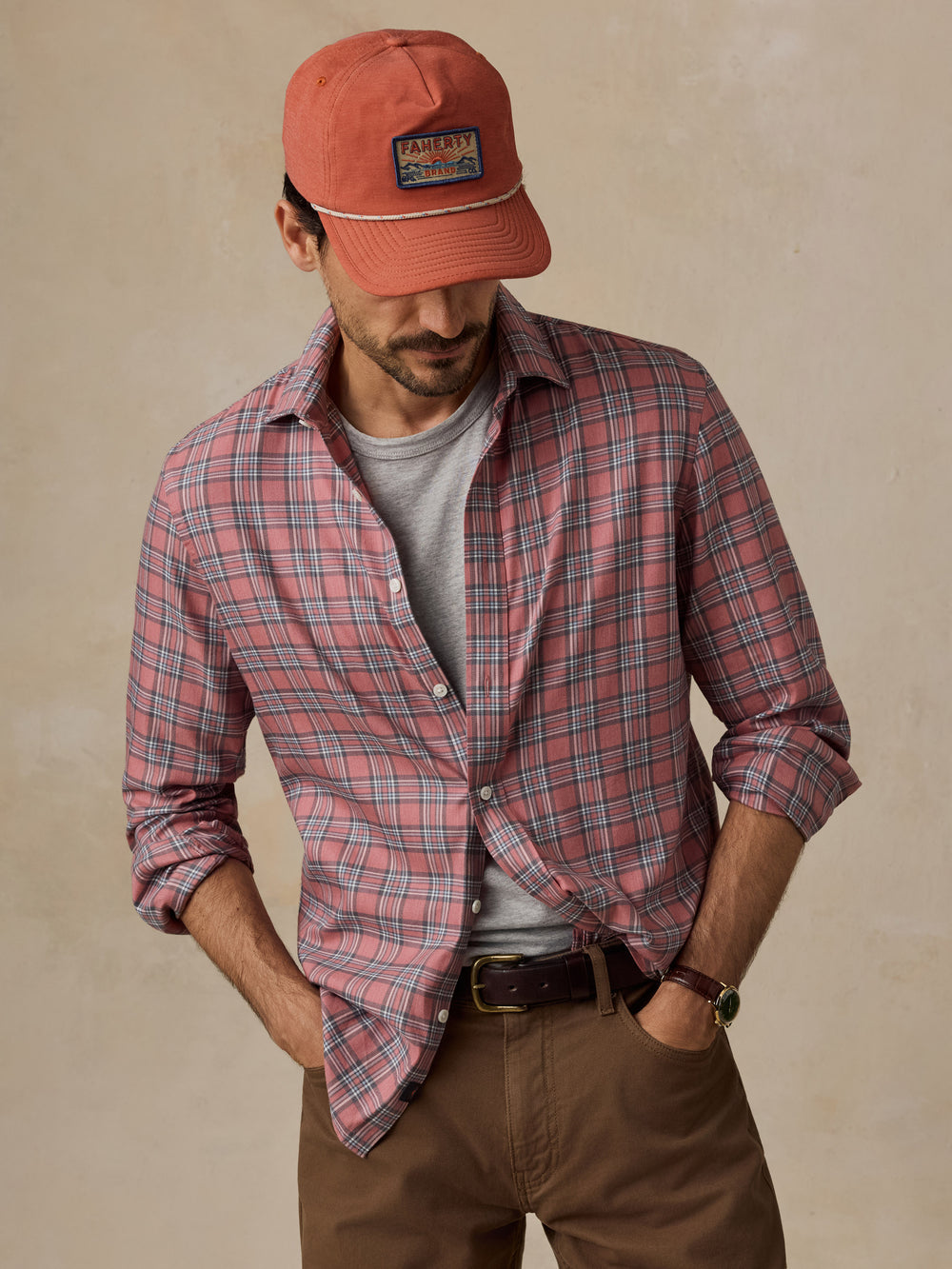Man in a red plaid shirt and rust cap with brown trousers