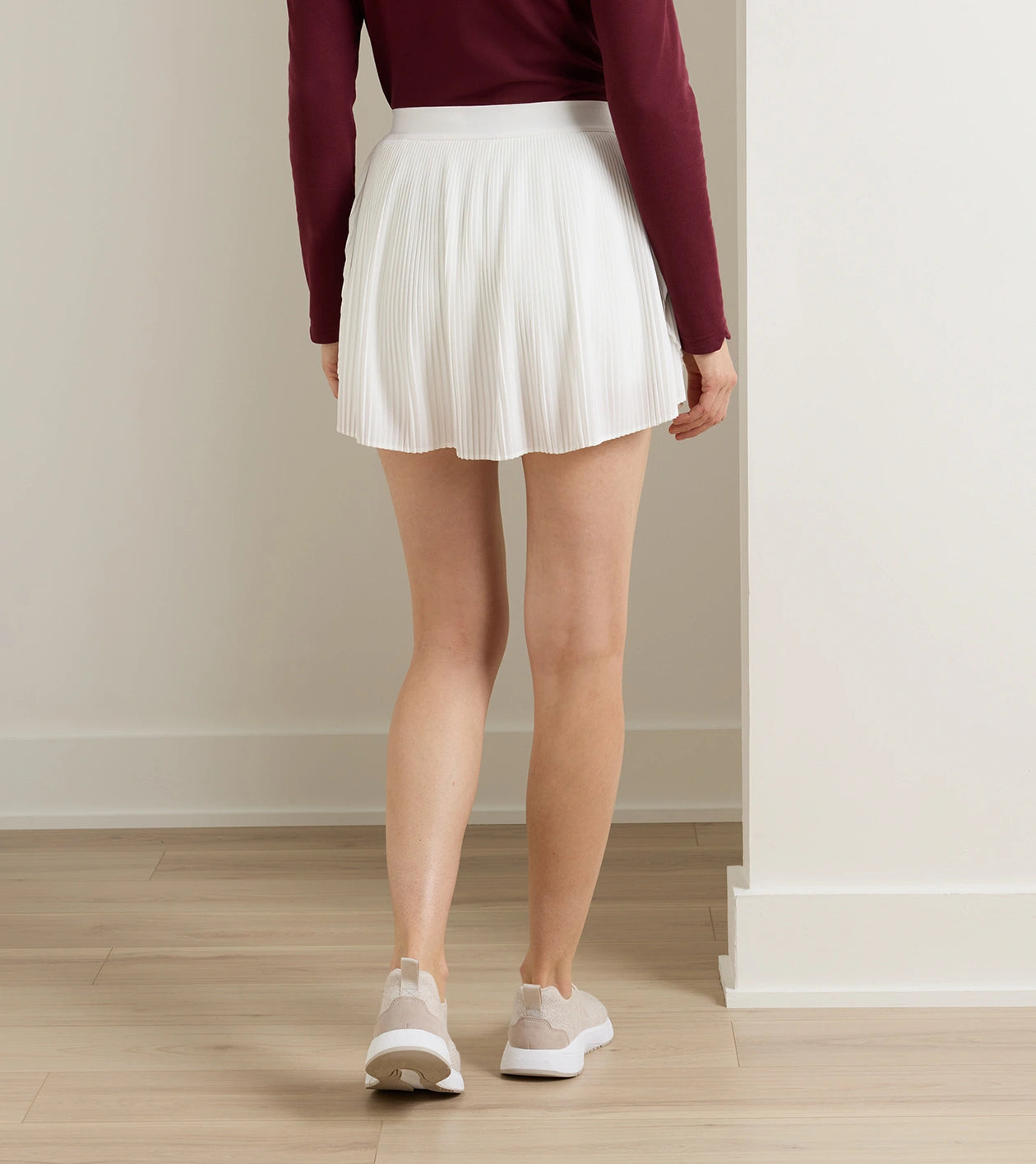Woman wearing Mickey Micro Pleat Skort in white stretch fabric styled with athletic shoes