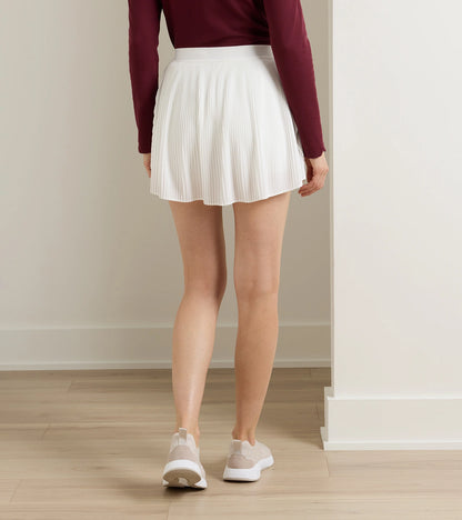Woman wearing Mickey Micro Pleat Skort in white stretch fabric styled with athletic shoes