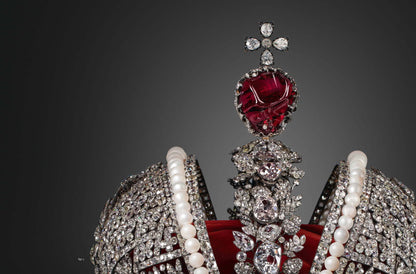 Close-up of an ornate jeweled crown featuring large red gemstones, pearls, and clear sparkling diamonds, showcasing craftsmanship in Diamonds Across Time: Facets Of Mankind.