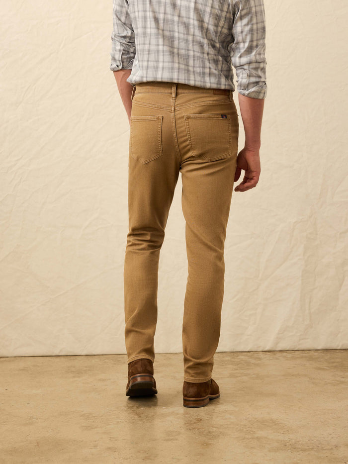 Man wearing tan pants and plaid shirt with leather boots from behind