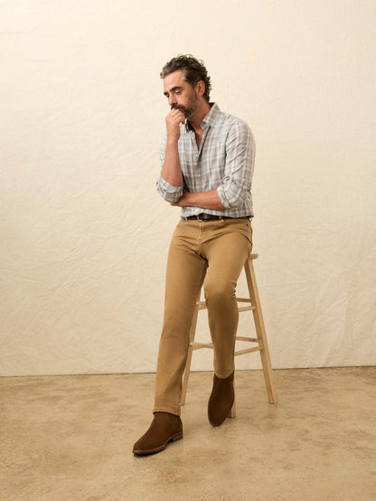 Man in a plaid shirt and tan trousers seated on a wooden stool Crawling.