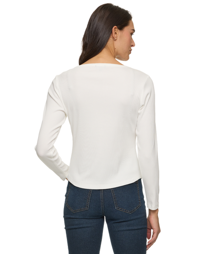 Woman seen from behind wearing a white long-sleeve top and dark blue jeans