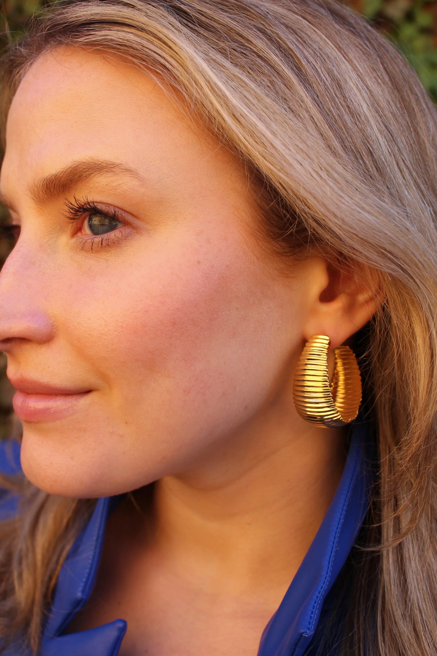 Gold ribbed Cobra Wide Hoop earrings on model, wide curved textured hoops