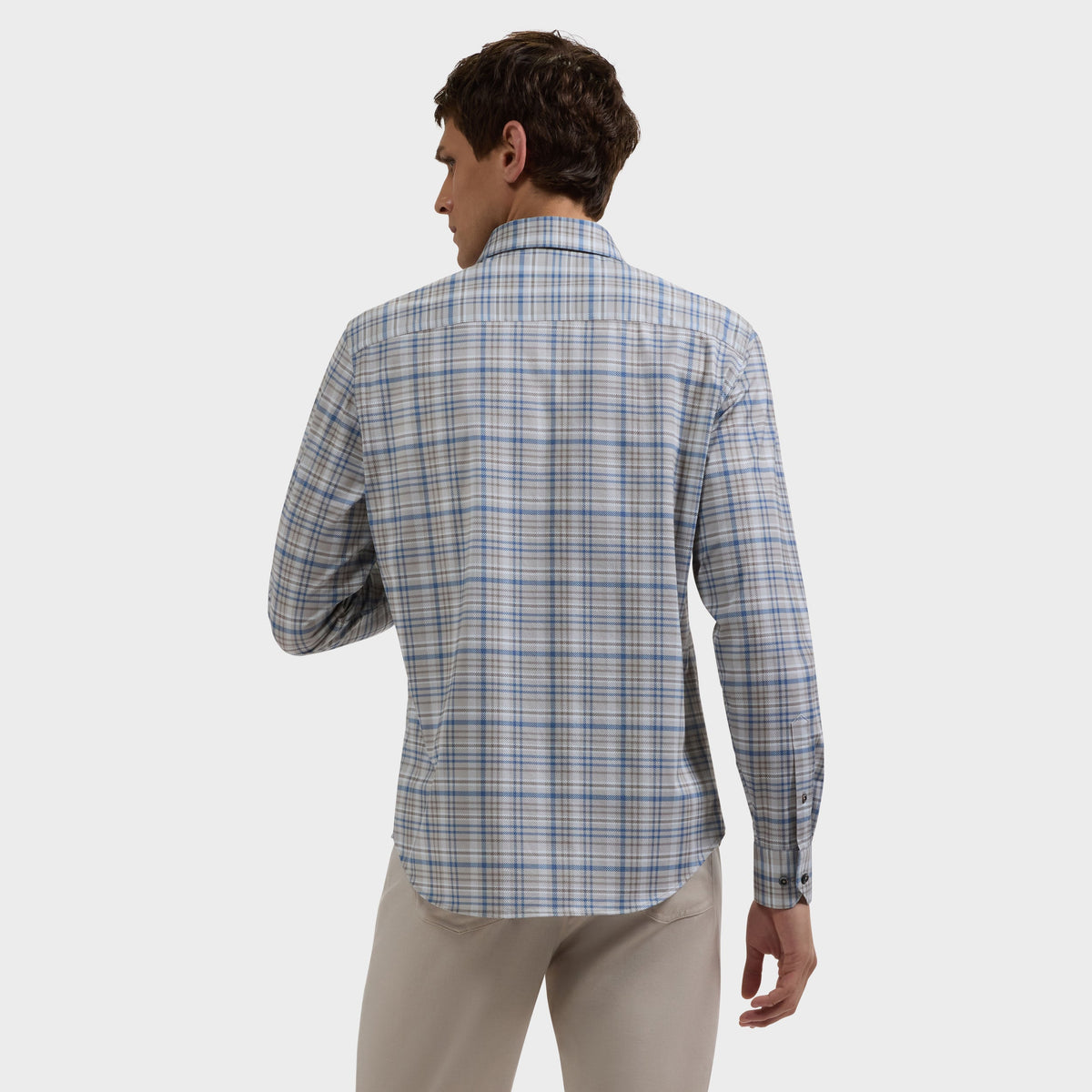 Man wearing a blue and gray plaid shirt with khaki pants, viewed from behind