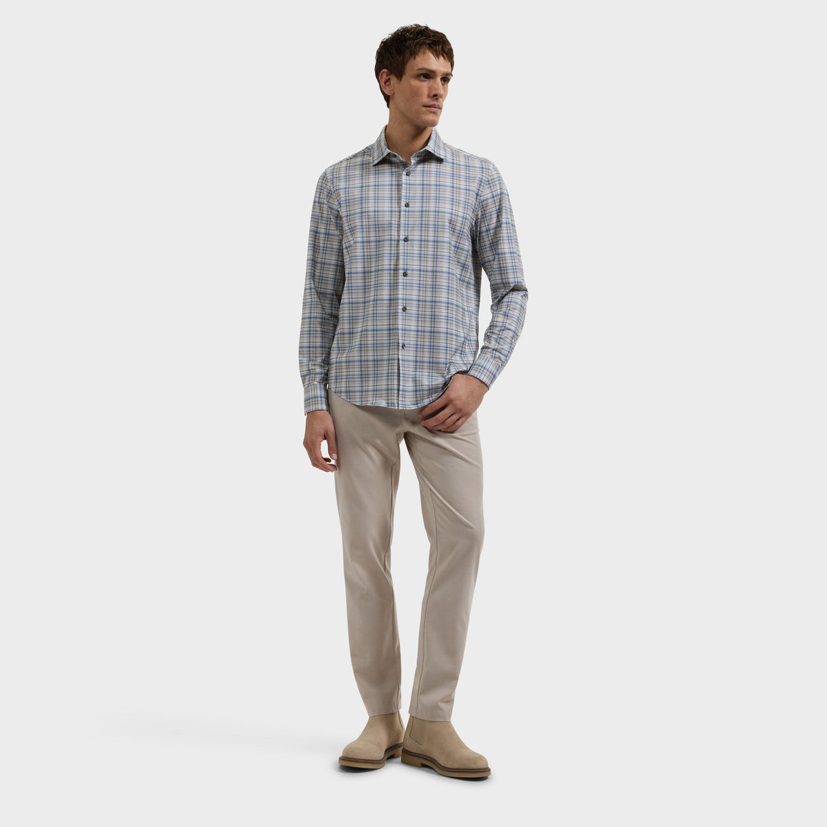 Man wearing a blue plaid shirt, khaki pants, and tan boots