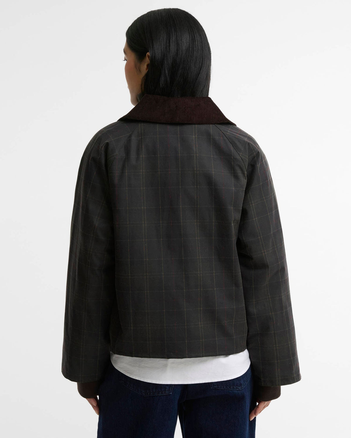 Woman seen from behind wearing a dark plaid jacket, white shirt, and jeans