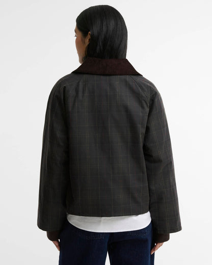 Woman seen from behind wearing a dark plaid jacket, white shirt, and jeans