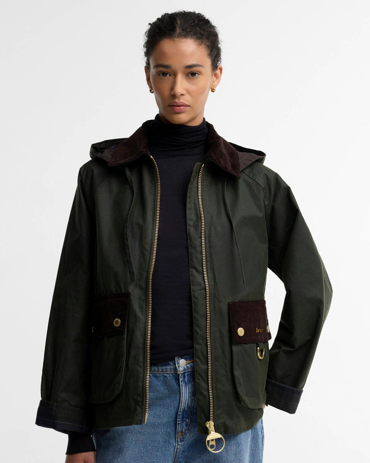 Model wearing a dark green jacket, black turtleneck, and blue jeans