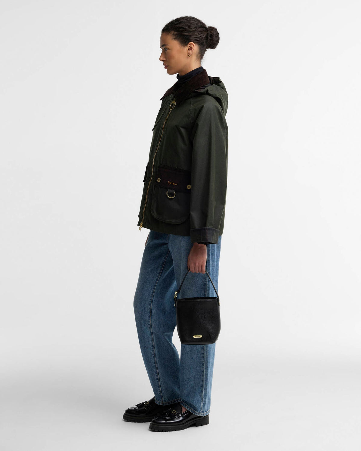 Woman wearing a dark jacket and jeans with a small black shoulder bag