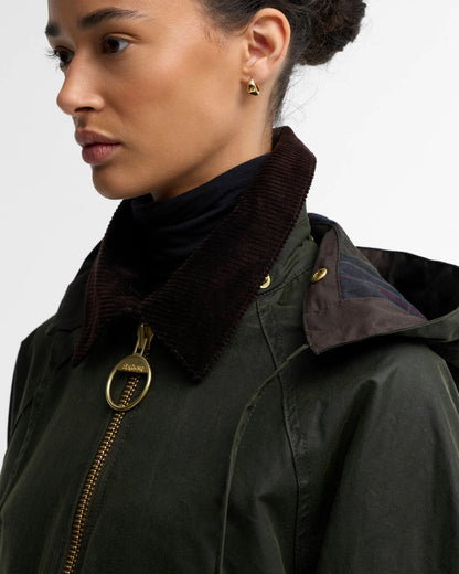Woman wearing a dark green jacket with a corduroy collar and gold zipper detail