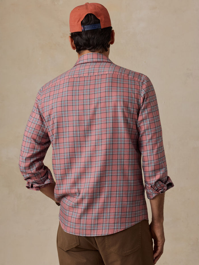 Person seen from behind wearing a red plaid shirt and backward cap