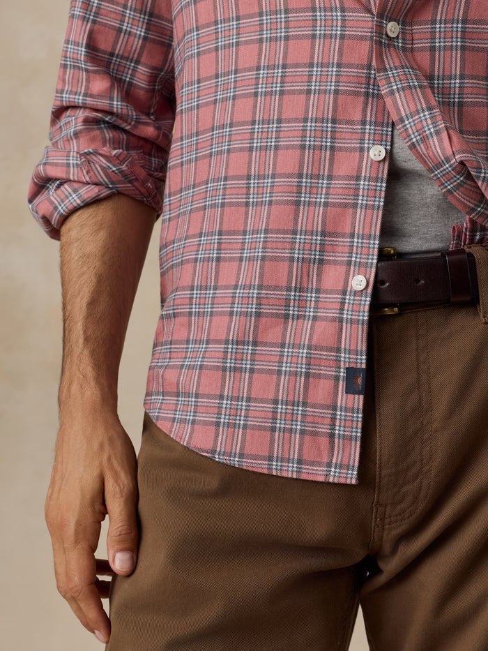 Man wearing a red plaid button-up shirt with brown pants and a leather belt