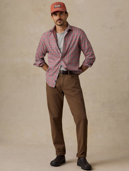 Man wearing a red plaid shirt, brown trousers, cap, and black boots