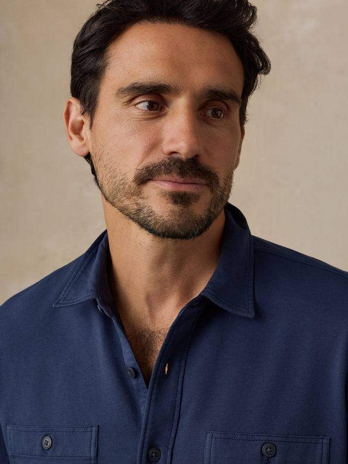 Bearded man wearing a navy blue collared shirt
