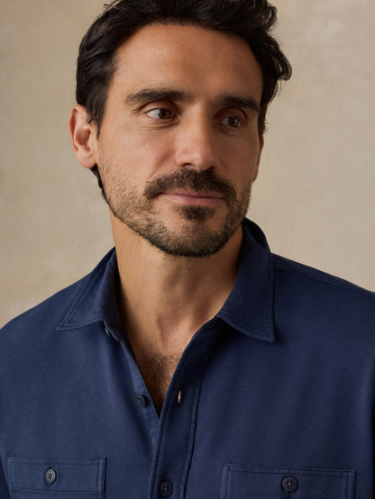 Bearded man wearing a navy blue collared shirt