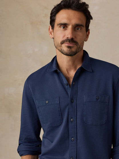 Man wearing a navy blue button-up shirt with two chest pockets against a neutral background
