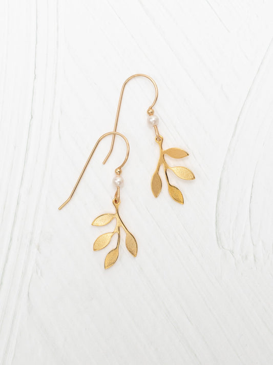 Delicate gold-tone earrings featuring a branch design with small leaves and a single pearl accent, showcasing the elegance of Holly Yashi Signature Earrings.
