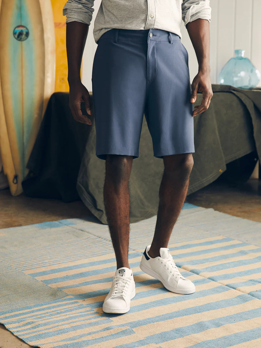 Man wearing dark blue Belt Loop All Day Shorts 9" - Msc0012 paired with white sneakers and a light gray shirt in a casual indoor setting, showcasing durable, high-quality fabric.