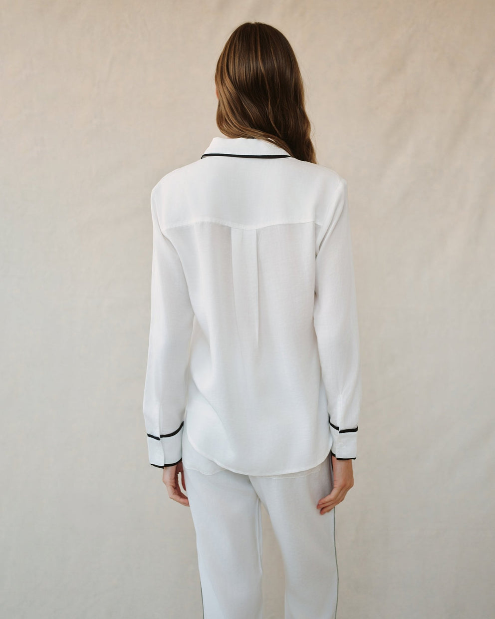 Back view of off-white shirt with contrast black collar band and button-cuff trim