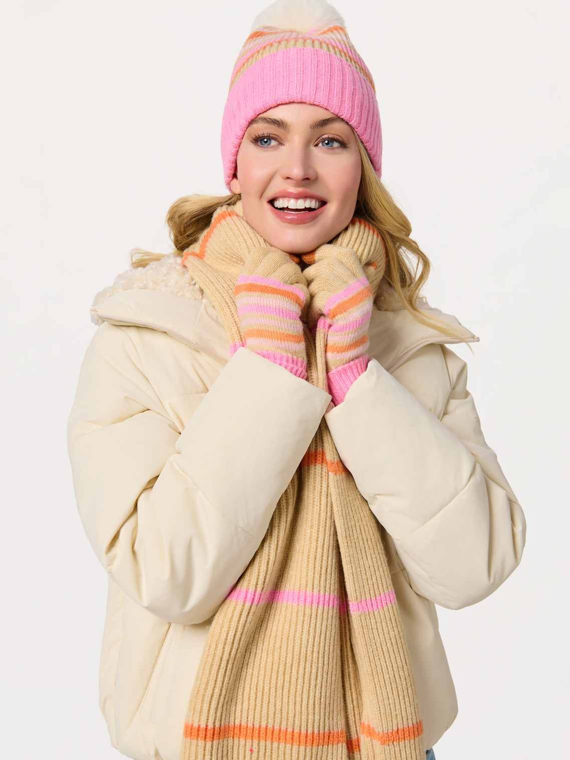 Woman wearing Elle Scarf striped in beige with pink and orange, styled with knit hat and gloves
