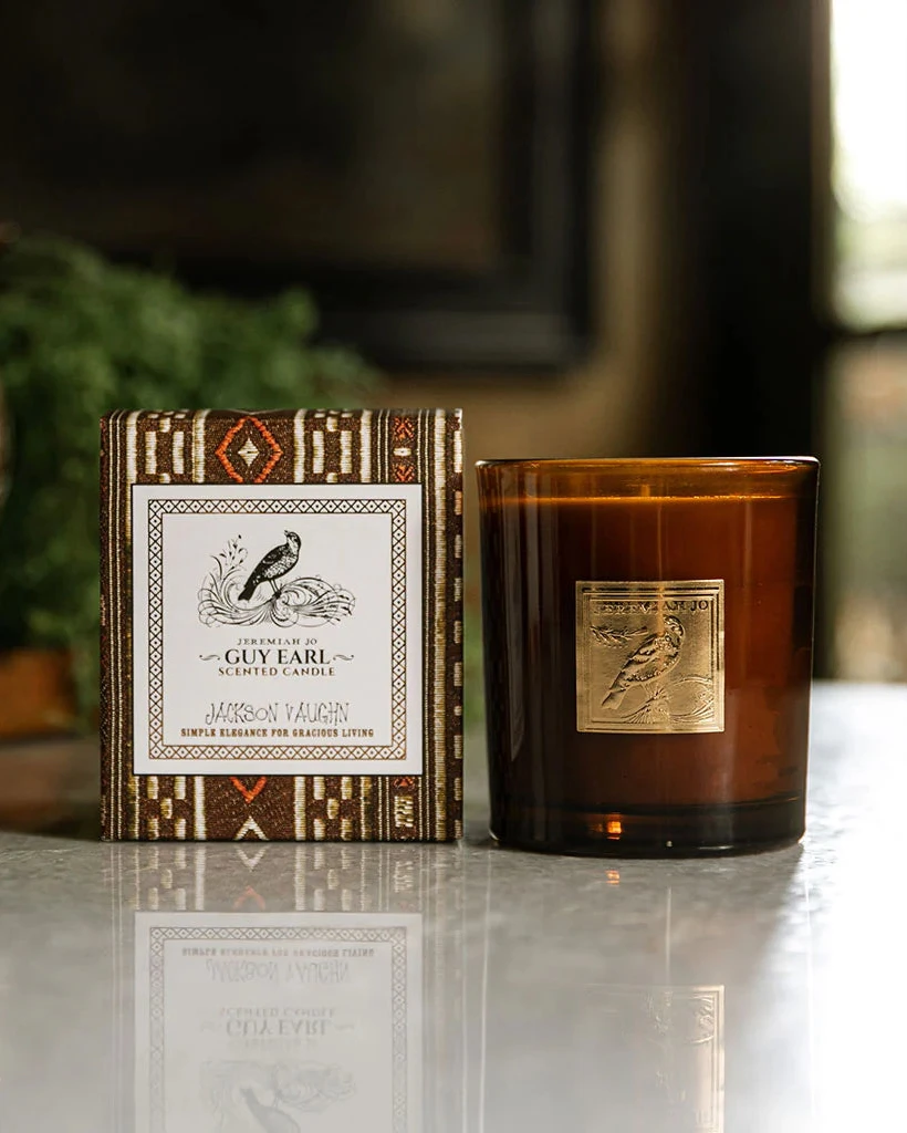 Guy Earl Candle in a brown glass jar beside a patterned decorative box, showcasing artisan home fragrance with a sophisticated, timeless style.