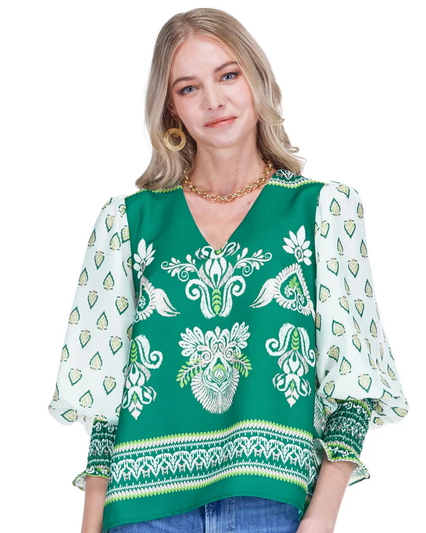 Woman wearing a green patterned blouse with a white background