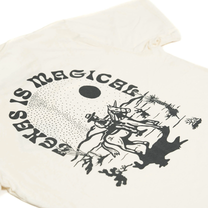 Cream-colored Texas Is Magical Tee featuring a whimsical black graphic of a unicorn with cacti and a sun, blending authentic Hill Country style with premium boutique quality.