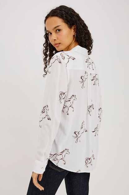 Woman wearing a white horse print shirt and dark jeans