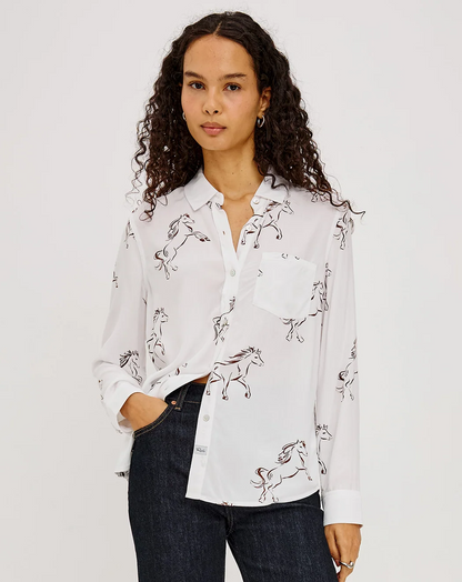 Woman wearing a white horse-print button-up shirt with dark jeans