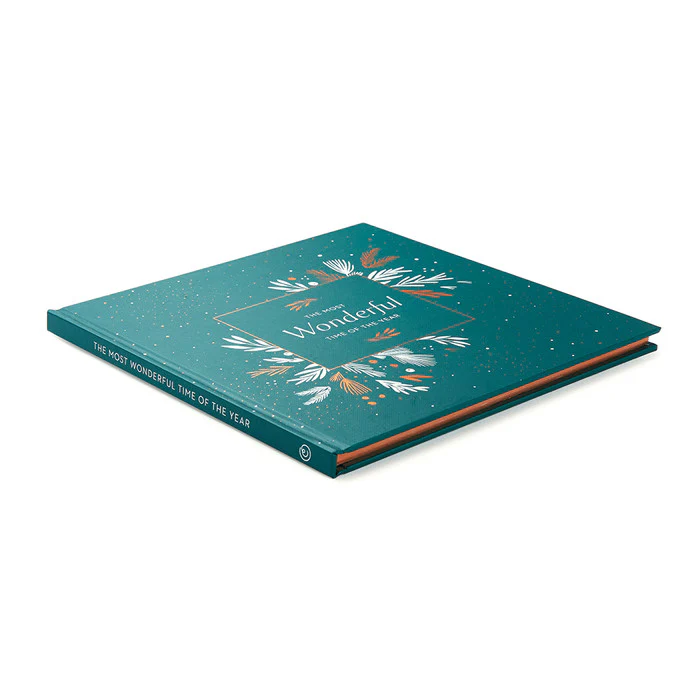 Hardcover book titled The Most Wonderful Time Of The Year with a teal cover adorned with gold and white botanical illustrations, reflecting a premium, personally curated style from Fredericksburg, Texas.
