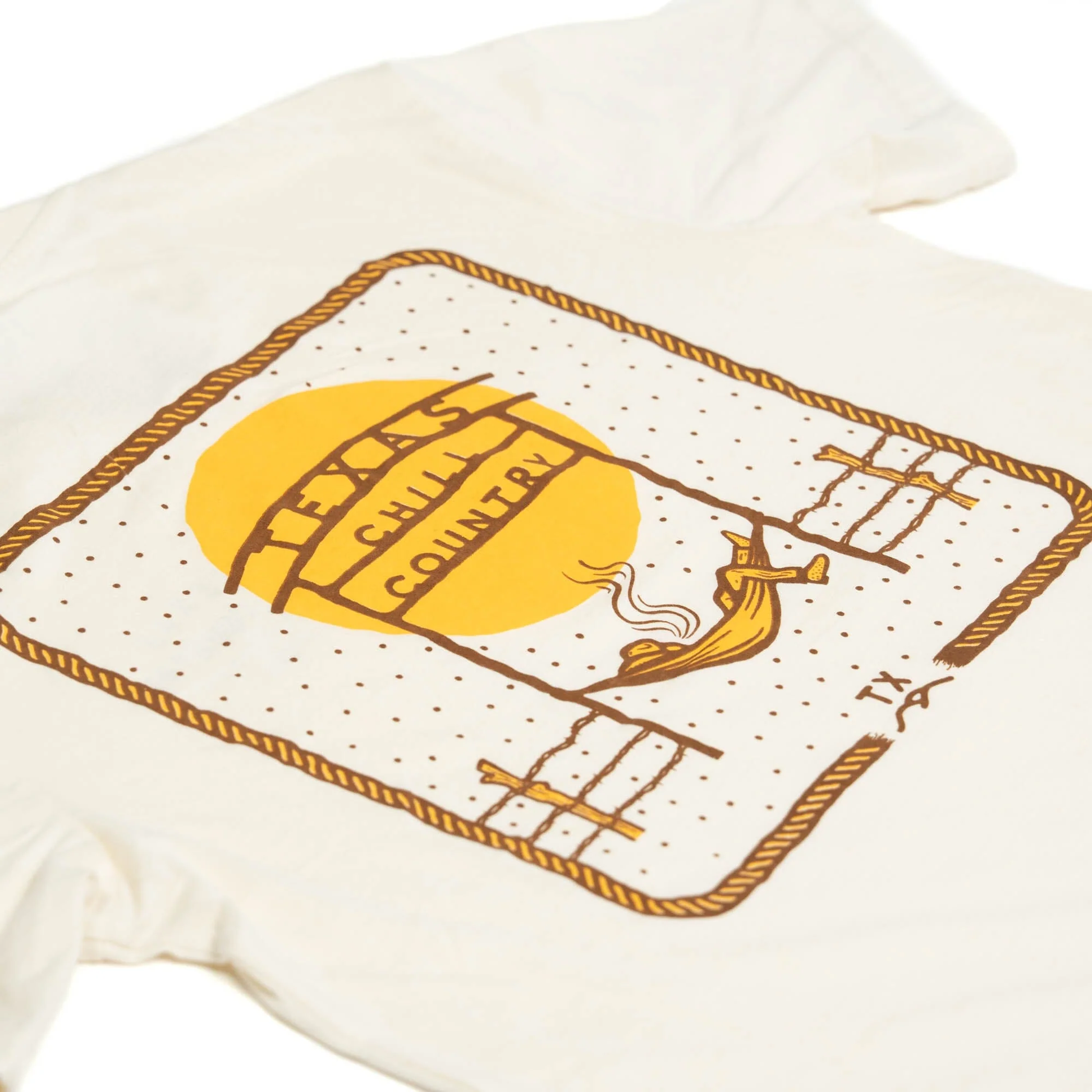 Chill Country Ranch Tee featuring a rustic Texas-themed graphic with warm mustard yellow and brown tones on a soft off-white fabric, embodying authentic Hill Country style.