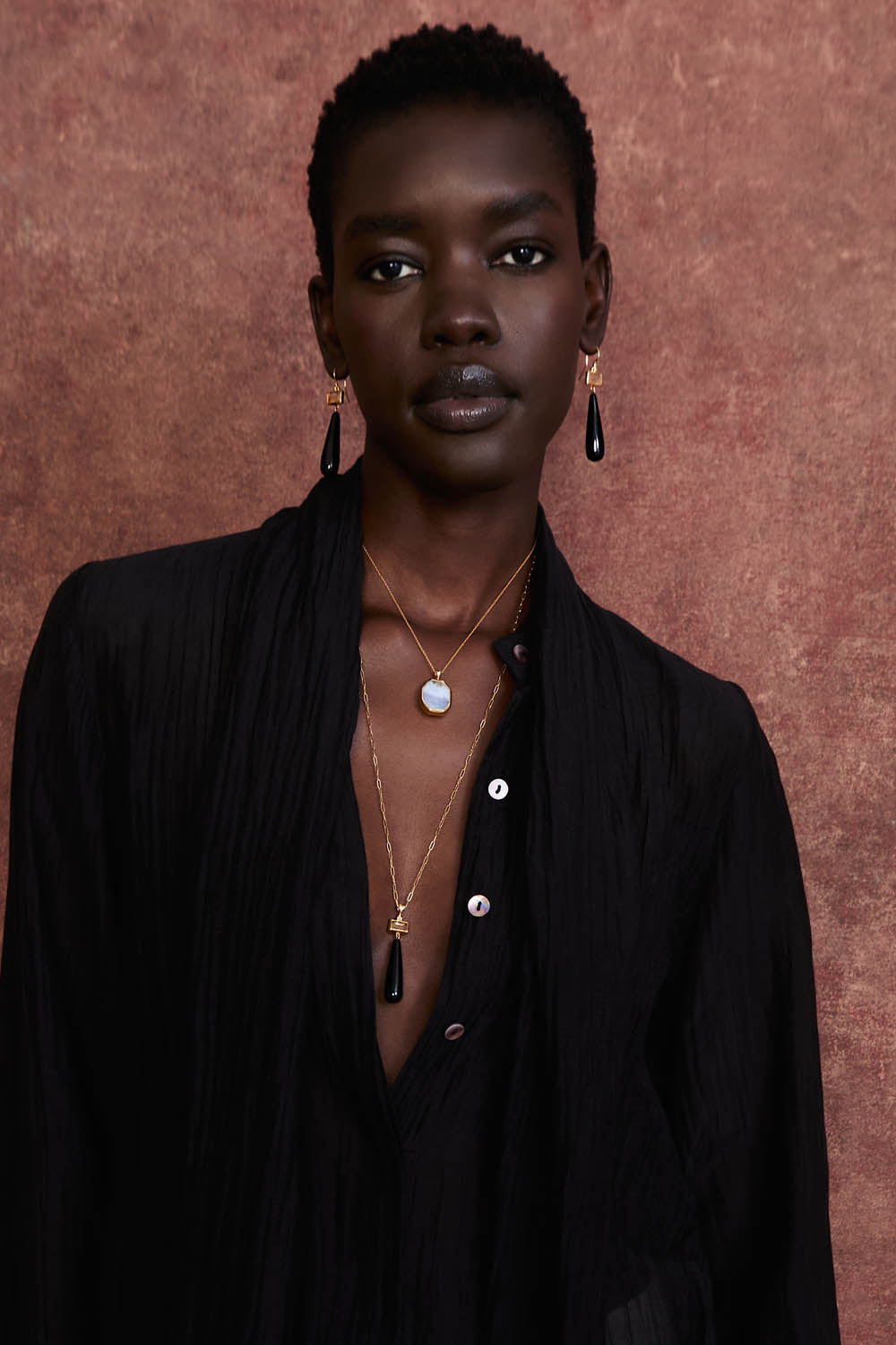 Model wearing black agate drop earrings—gold rectangles with black teardrop stones