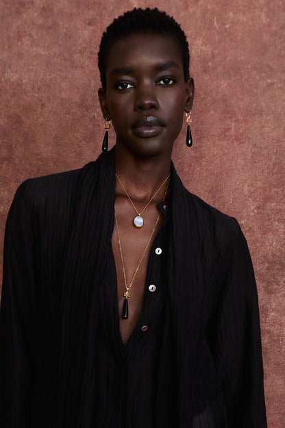 Model wearing black agate drop earrings—gold rectangles with black teardrop stones