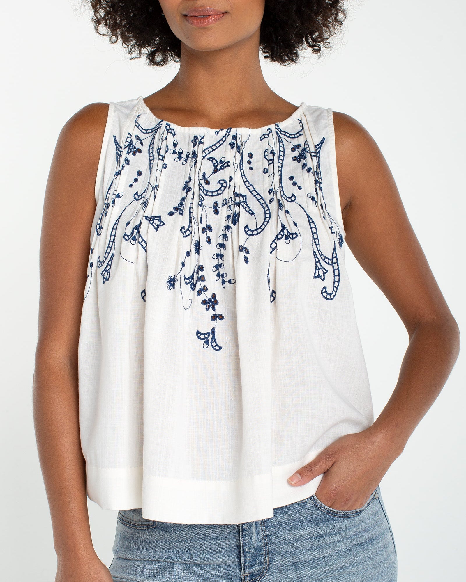 Sleeveless Boat Neck Woven Top W/ Pintucks in white with blue floral embroidery detailing